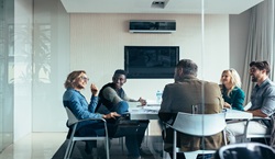 Adults sat around table in meeting room